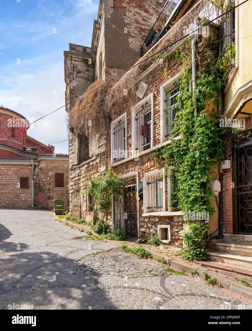 Kopfsteinpflaster-Gasse mit wunderschönen alten, traditionellen roten Backsteinhäusern im Balat-Viertel, an einem Sommertag, Istanbul, Türkei Stockfoto