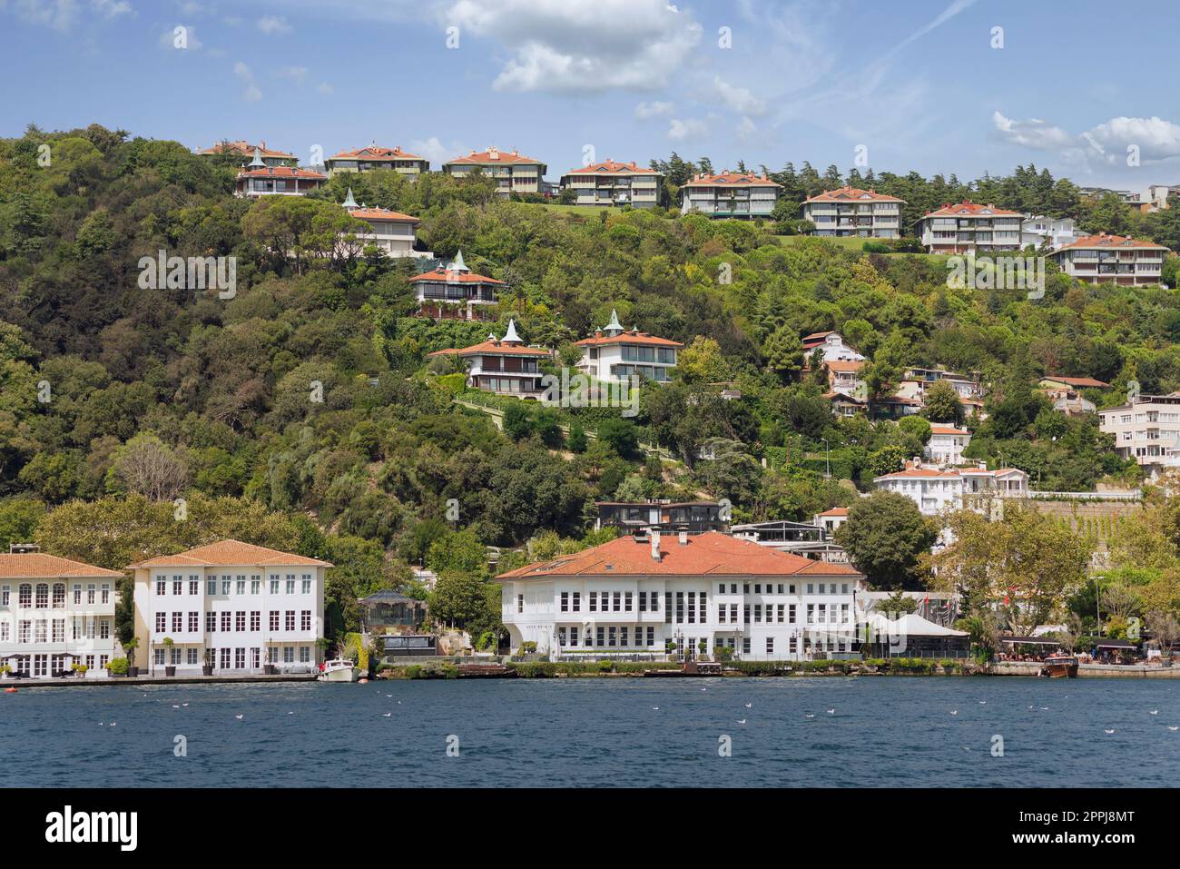 Blick vom Meer auf die grünen Berge auf der europäischen Seite des Bosporus, mit traditionellen Häusern, Istanbul, Türkei Stockfoto