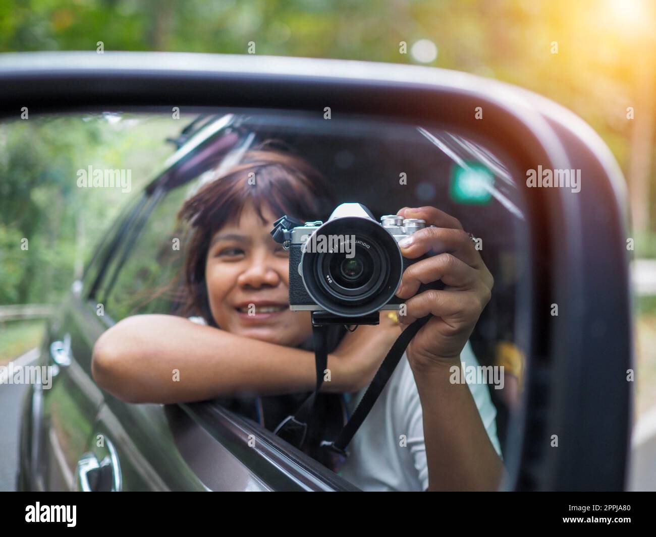 Eine Frau hält eine Digitalkamera in der Hand und macht ein Bild von sich selbst, das im Spiegel reflektiert wird. Stockfoto