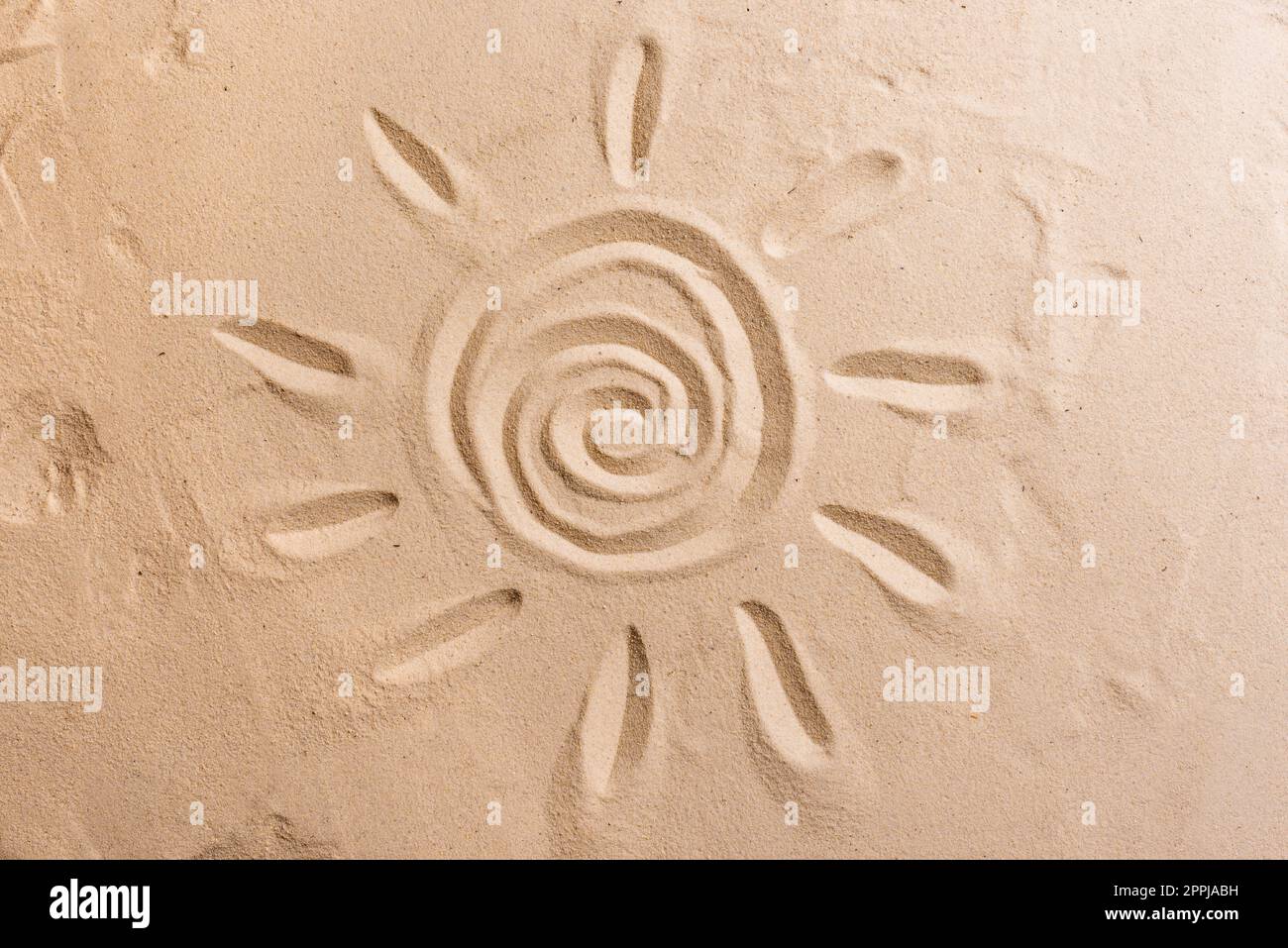 Sonnensymbol auf Sand, sandige Strandstruktur. Frohes Weihnachtskonzept. Stockfoto