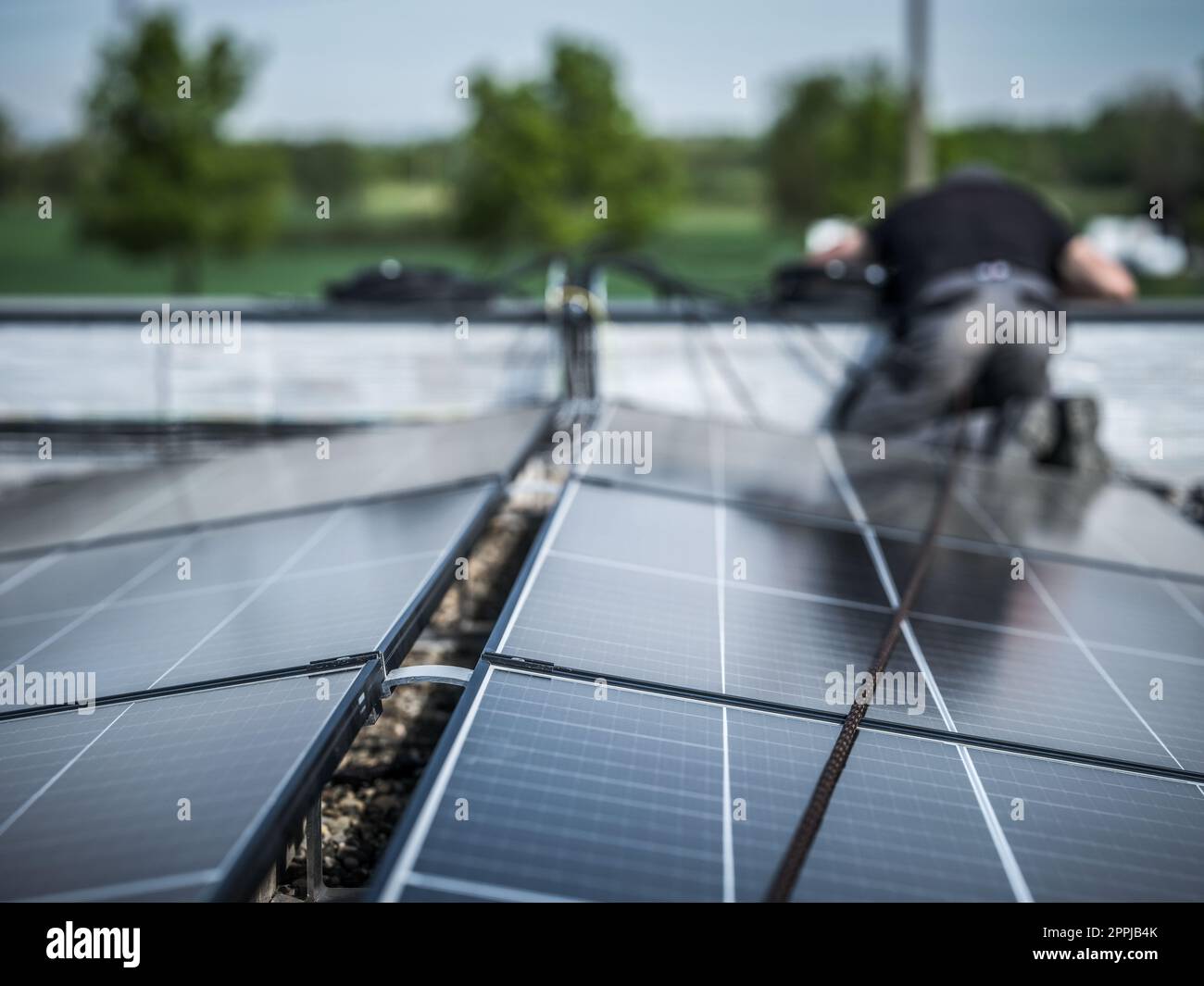 Männliche Teamingenieure, die eigenständige Solarpaneele installieren. Elektriker montieren blaues Solarmodul auf dem Dach eines modernen Hauses. Konzept alternativer Energien Stockfoto