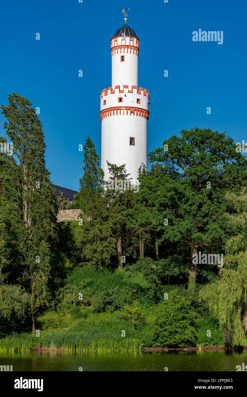 Der weiße Turm der Burg Bad Homburg mit den grünen Bäumen und dem wolkenlosen blauen Himmel Stockfoto