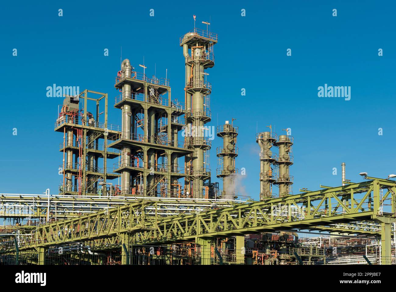 Grüne Schornsteine, Rohre und Metallgitter gegen den blauen wolkenlosen Himmel in der Chemiefabrik Stockfoto