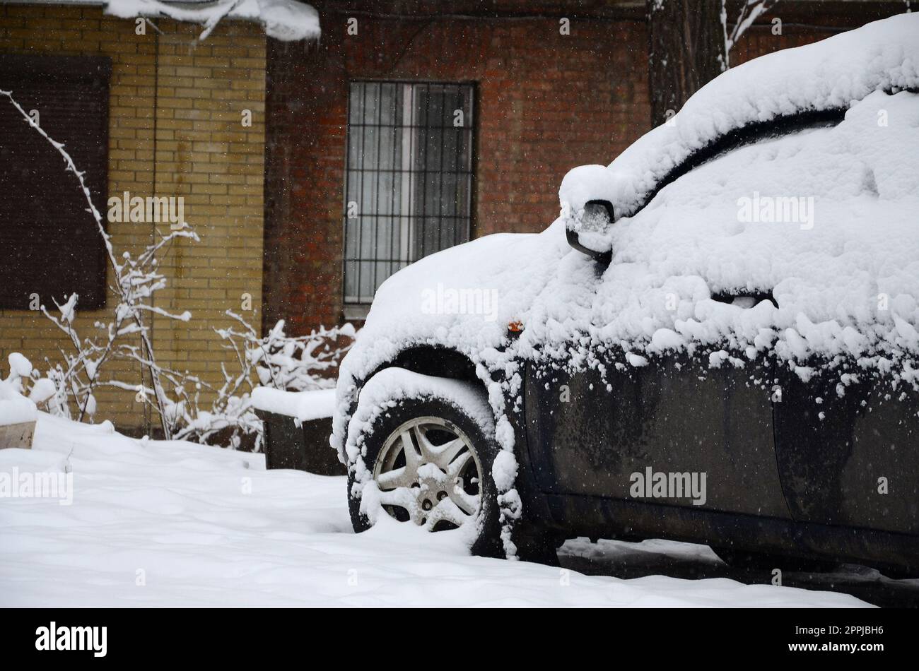 Fragment des Autos unter der Schneeschicht nach dem starken Schneefall. Die Karosserie des Autos ist mit weißem Schnee bedeckt Stockfoto