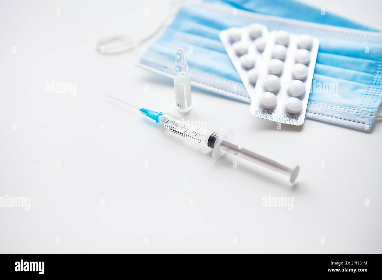 Vorbereitung zur Impfung gegen Covid-19. Spritze, Impfstoff, Pillen, medizinische Maske. Stockfoto