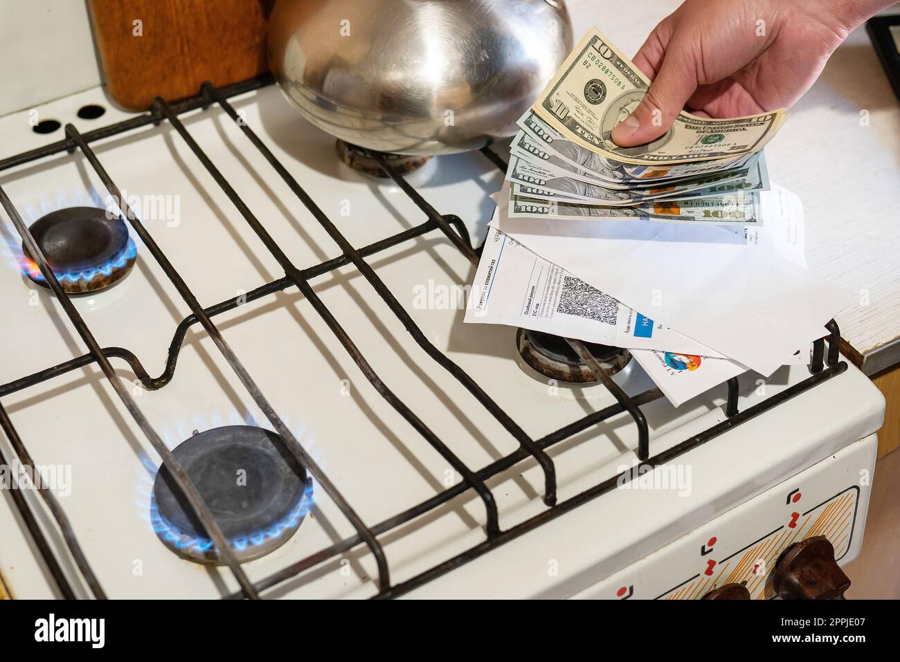 Zahlung von Versorgungsleistungen. Dollarscheine, Stromrechnungen werden in der Nähe eines brennenden Gasbrenners gehalten. Das Konzept der Erhöhung der Kosten für die Erdgasversorgung und -Bezahlung. Stockfoto