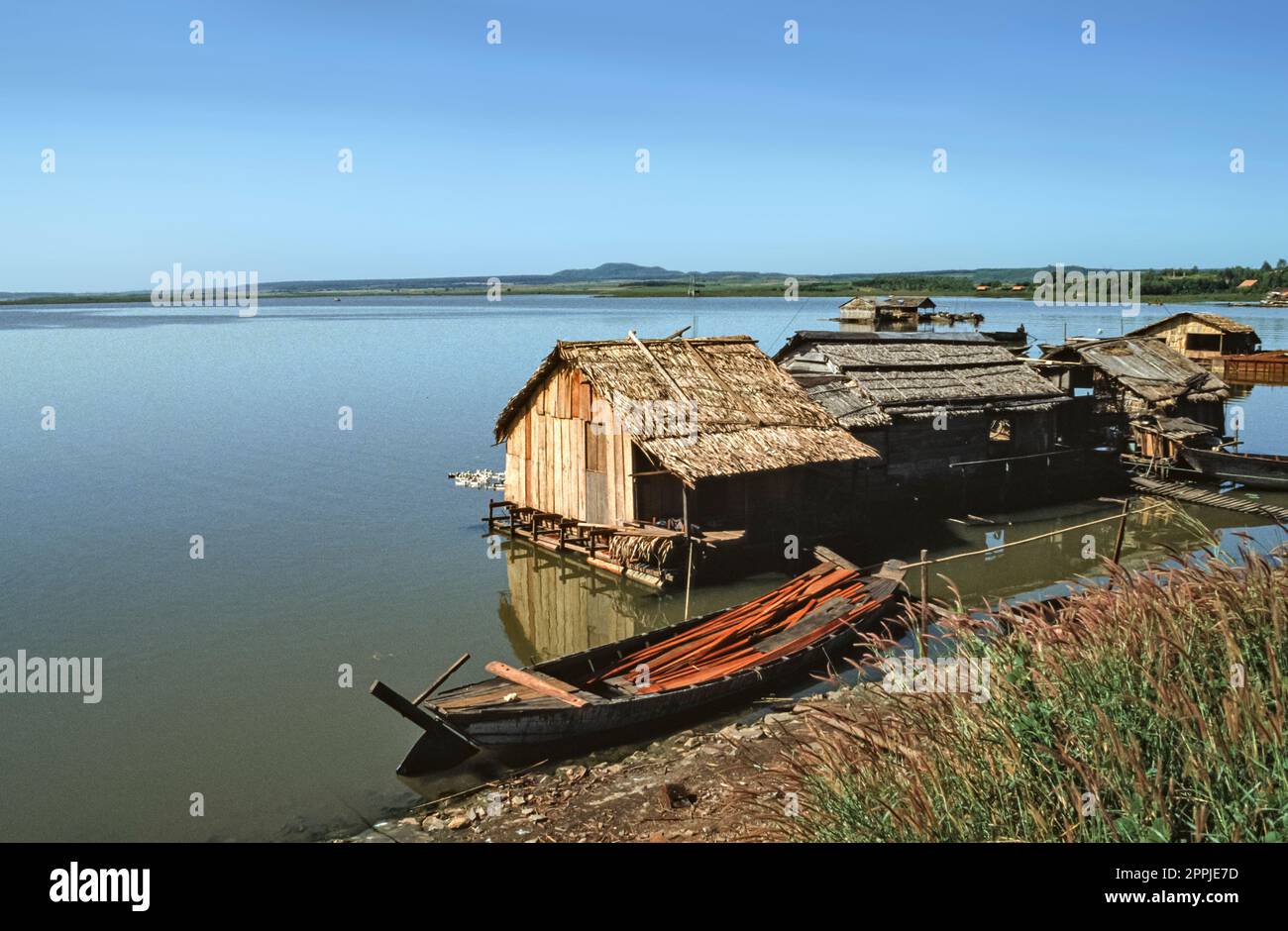 Gescannte Folie mit historischem Farbfoto von Fischerbooten, die in einer Siedlung am Ufer eines Sees im Zentrum Vietnams anlegen Stockfoto