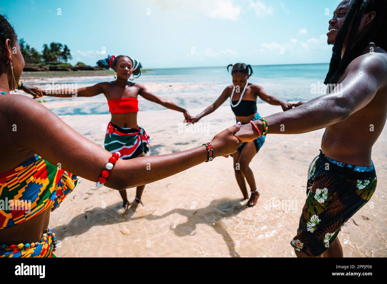 Einheimische mit typisch kenianischen Klamotten, die am Strand tanzen Stockfoto