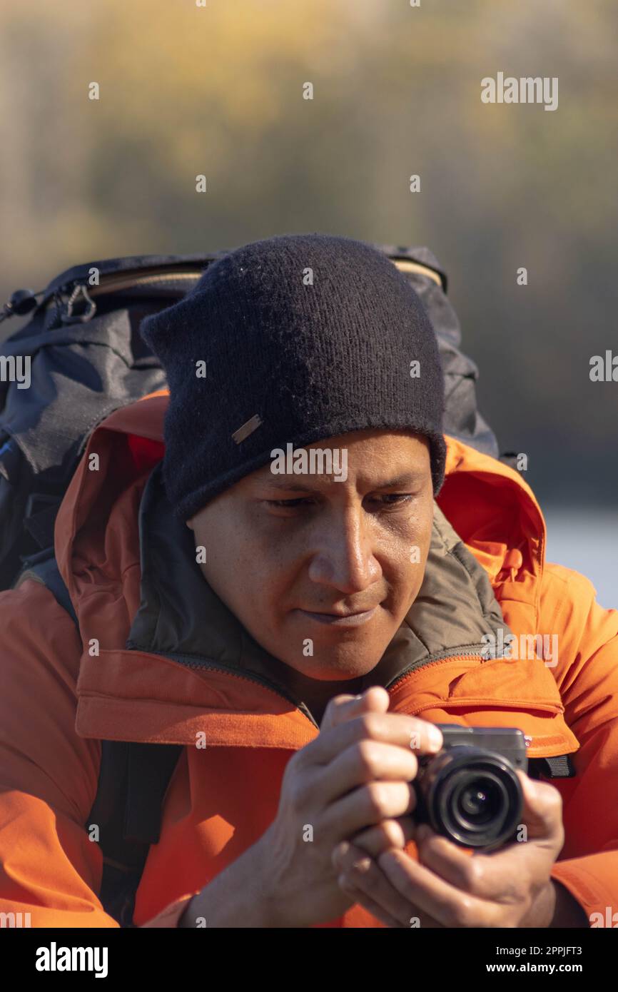 Porträt eines Reisenden am See im Herbst, der ein Foto mit der Digitalkamera machte Stockfoto