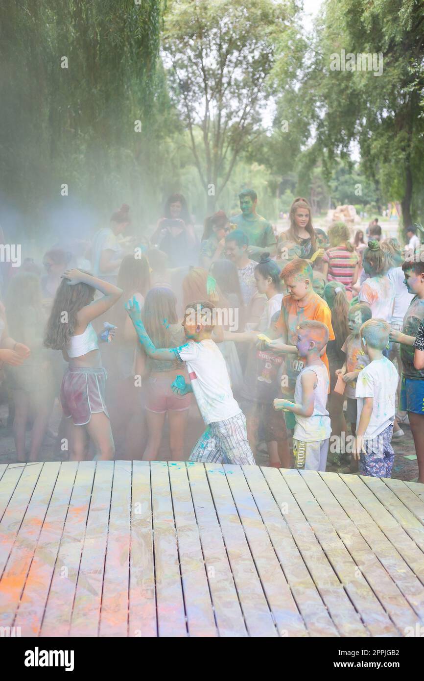 Lemberg, Ukraine - 18. Juli 2021: Color Holi Festival, eine Menschenmenge von Erwachsenen und kleinen Kindern werfen farbenfrohe Farben. Indianerfeiertag, Kinder laufen auf einer Holzbühne. Stockfoto