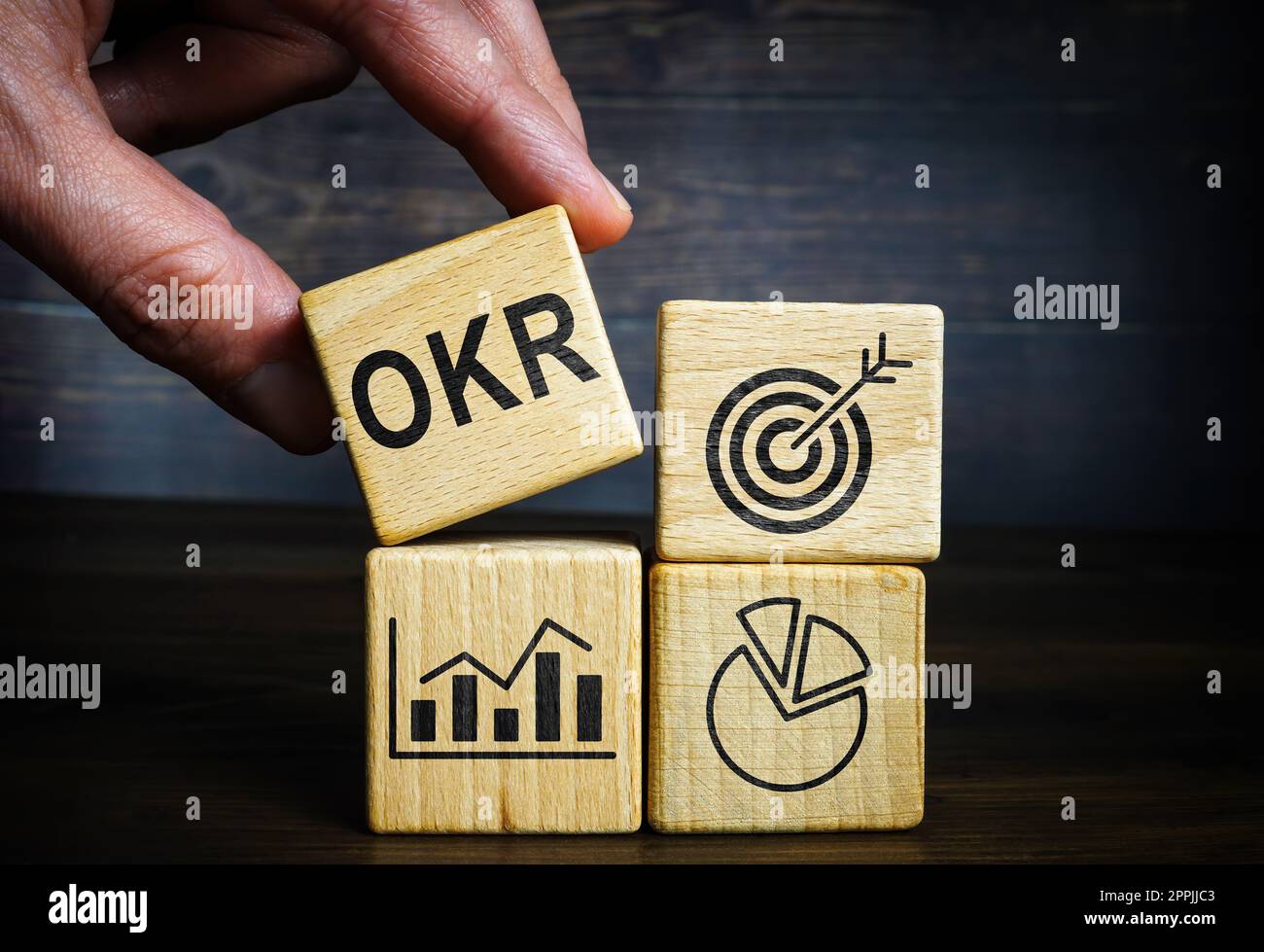 Die Hand hält den Würfel neben den anderen. OKR-Ziele und wichtigste Ergebnisse. Stockfoto