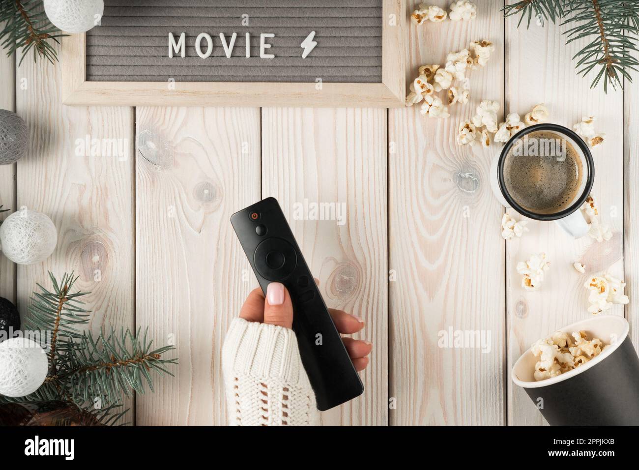 Gekürzte Frau Hände im Pullover mit Fernbedienung, Namensschild-Film, Kaffeetasse, Popcorn auf xmas Holzhintergrund Stockfoto