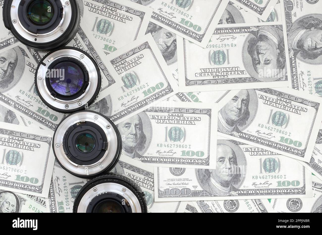 Ein paar fotografische Linsen liegen auf dem Hintergrund vieler Dollarscheine. Platz für Text Stockfoto