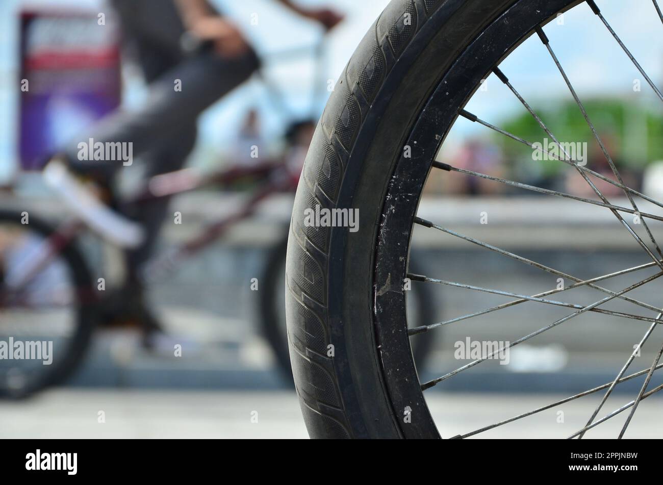 Ein BMX Fahrrad Rad vor dem Hintergrund einer unscharfen Straße mit Radfahren Reiter. Extreme Sport Konzept Stockfoto