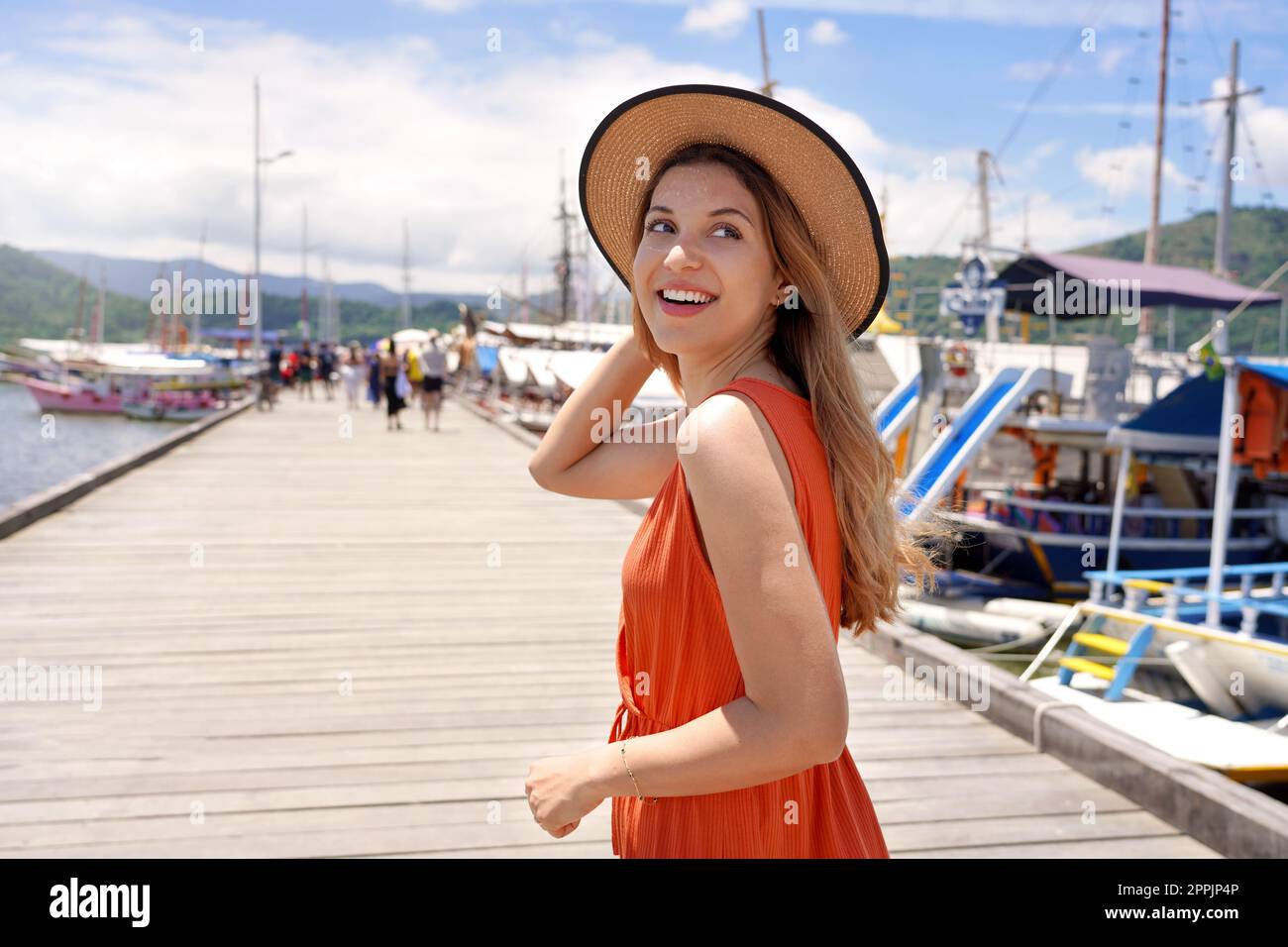 Portrait einer lächelnden Touristin, die auf einem hölzernen Pier spaziert und mit der Fähre oder einem gemieteten Boot oder einer Yacht die warmen tropischen Ziele erkundet Stockfoto