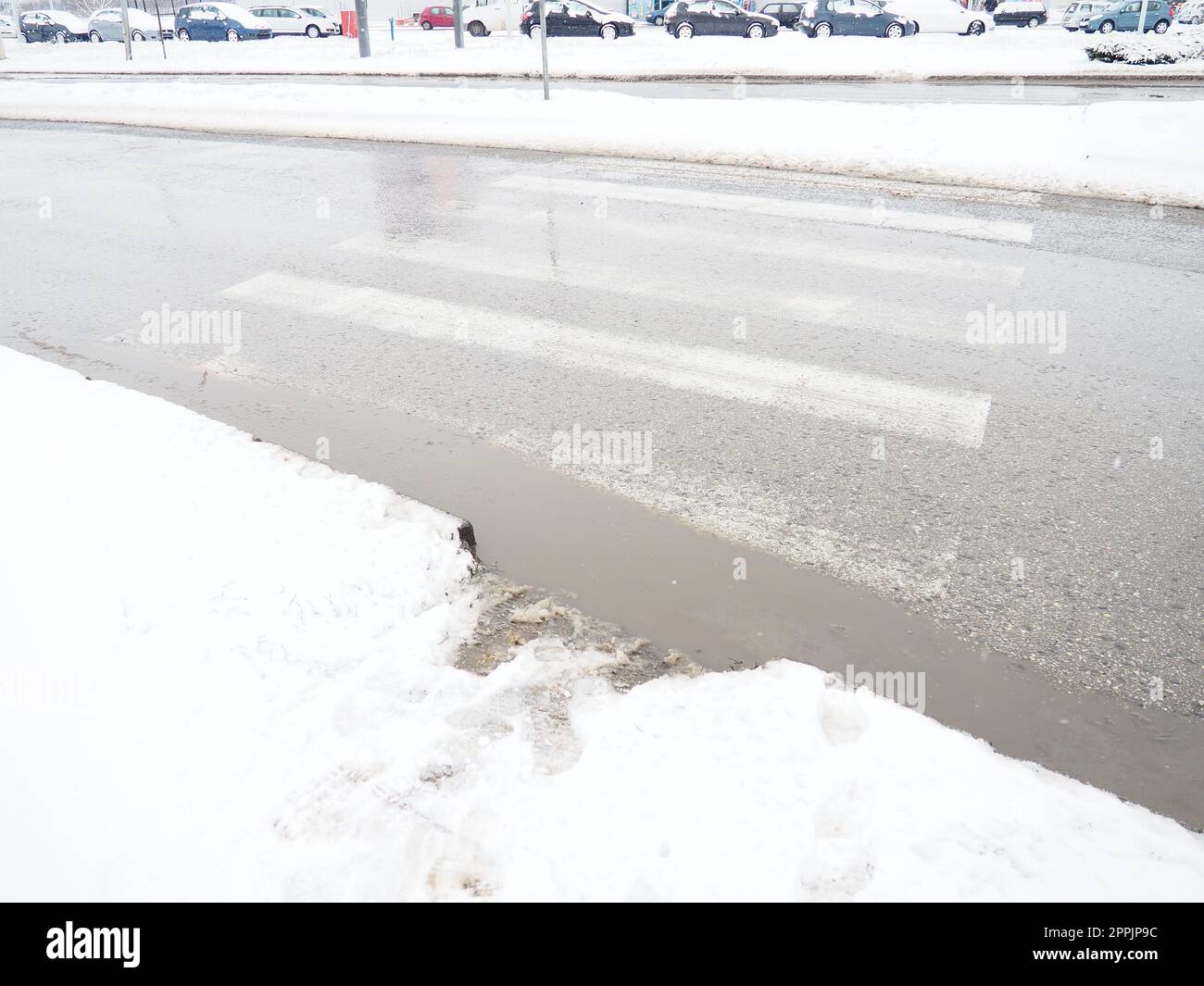 Schnee, Eis, Matsch und Winterschlamm an einer Fußgängerüberquerung. Die Lufttemperatur beträgt etwa 0 °C. Schwierige Fahrbedingungen. Bremsweg des Fahrzeugs. Verkehrsgesetze. Infrastruktur und Straßendienste Stockfoto