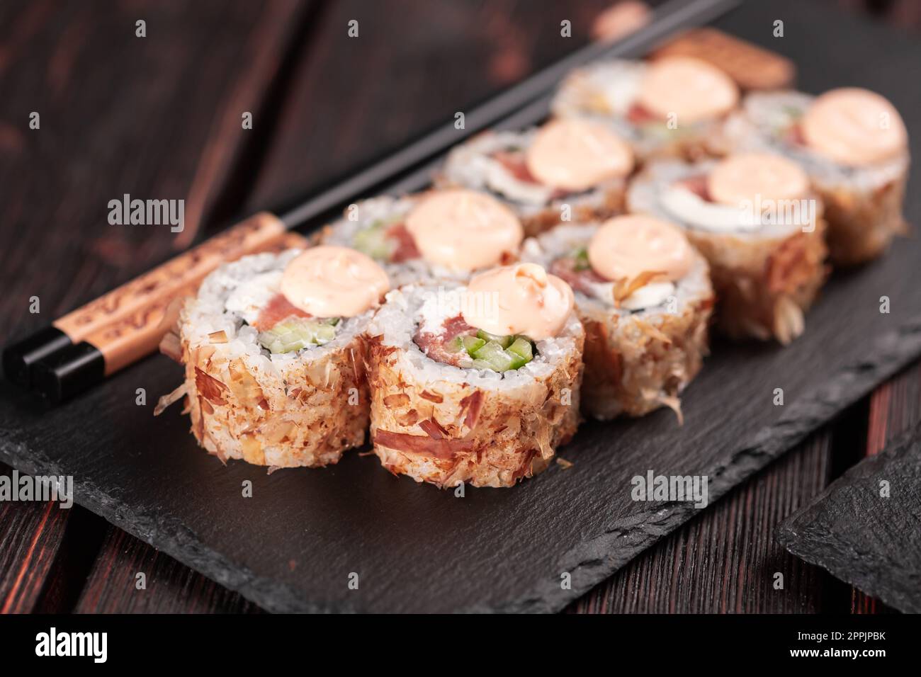 Lachs-Sushi-Brötchen mit Thunfischflocken und Souse aus nächster Nähe - asiatische Sushi-Gerichte und japanische Gerichte Stockfoto