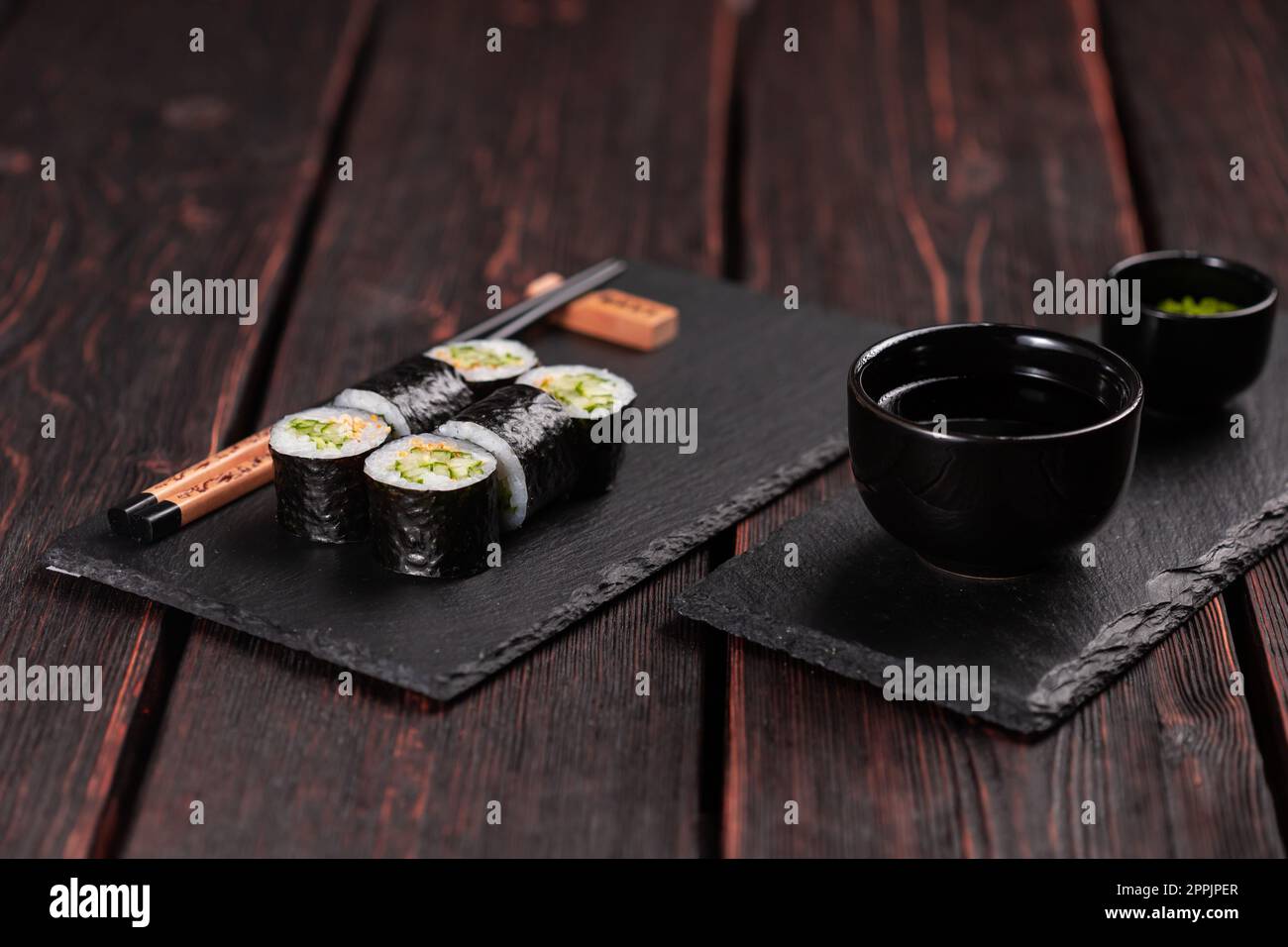 Maki Sushi-Brötchen mit Gurke und Sesam mit Essstäbchen. Sushi-Menü. Japanisches Essen. Stockfoto