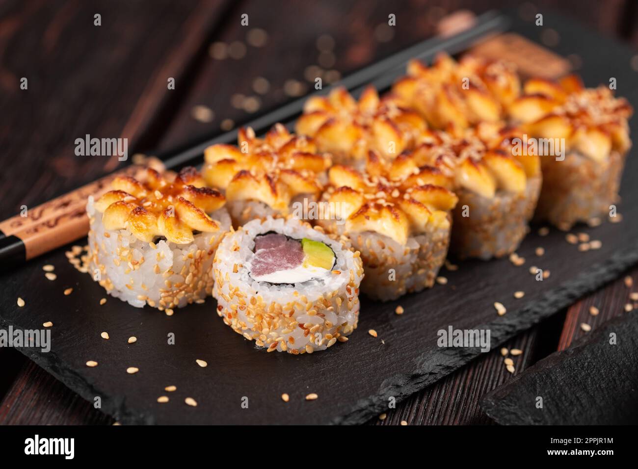 Sushi-Brötchen mit geräuchertem Thunfisch mit Avocado und Käse aus nächster Nähe. Traditionelles, köstliches, frisches Sushi-Brötchen. Sushi-Menü. Japanisches Restaurant. Asiatisches Essen Stockfoto