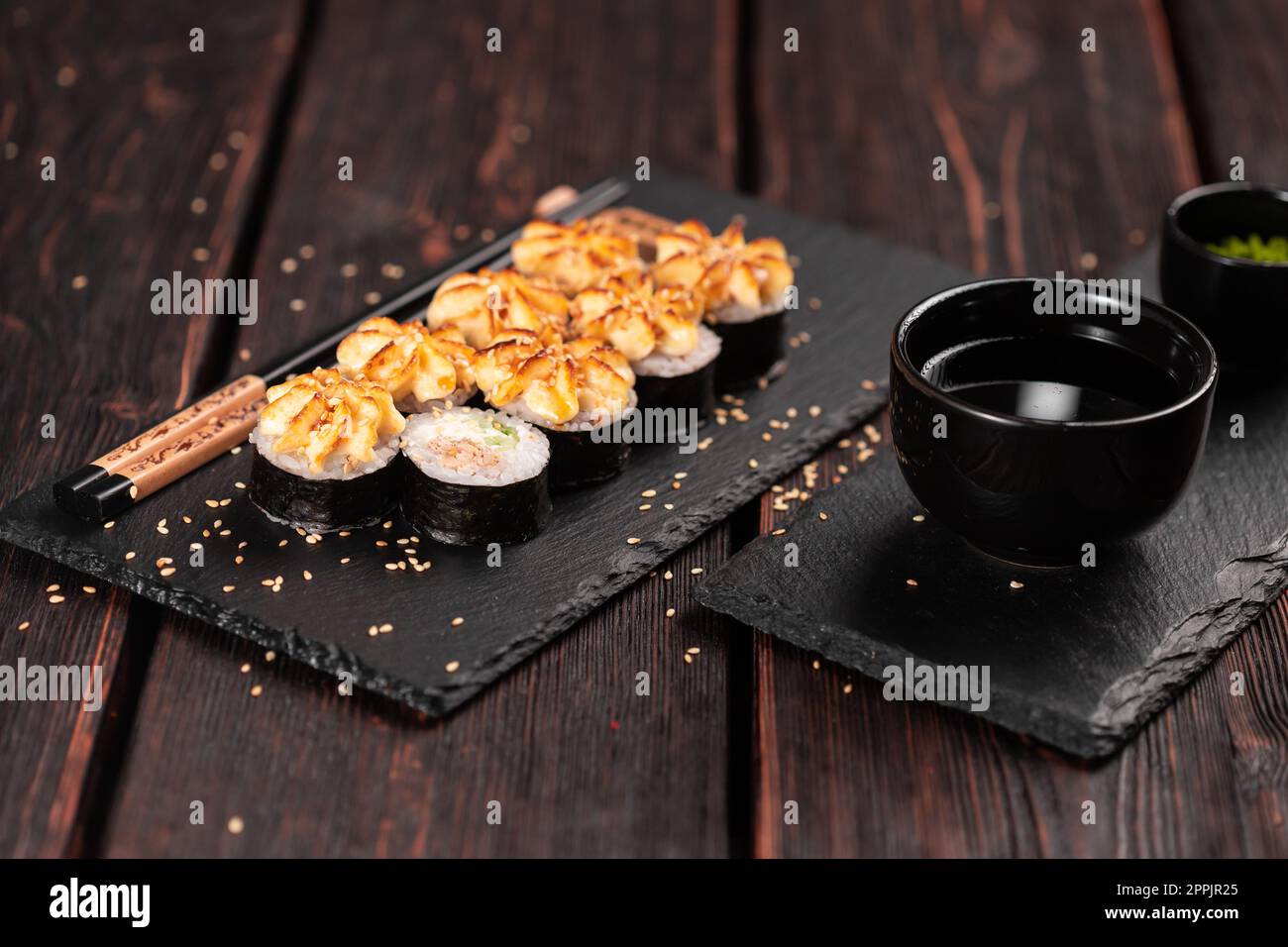 Maki Sushi Brötchen mit Aal und Gurke serviert auf schwarzem Brett aus nächster Nähe - japanische Küche Stockfoto