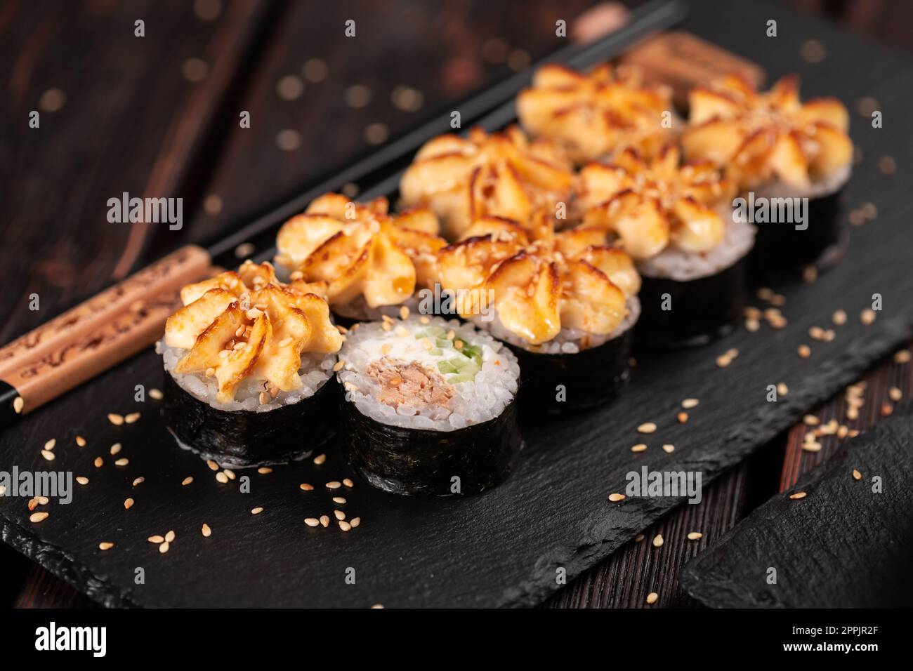 Maki Sushi Brötchen mit Aal und Gurke serviert auf schwarzem Brett aus nächster Nähe - japanische Küche Stockfoto