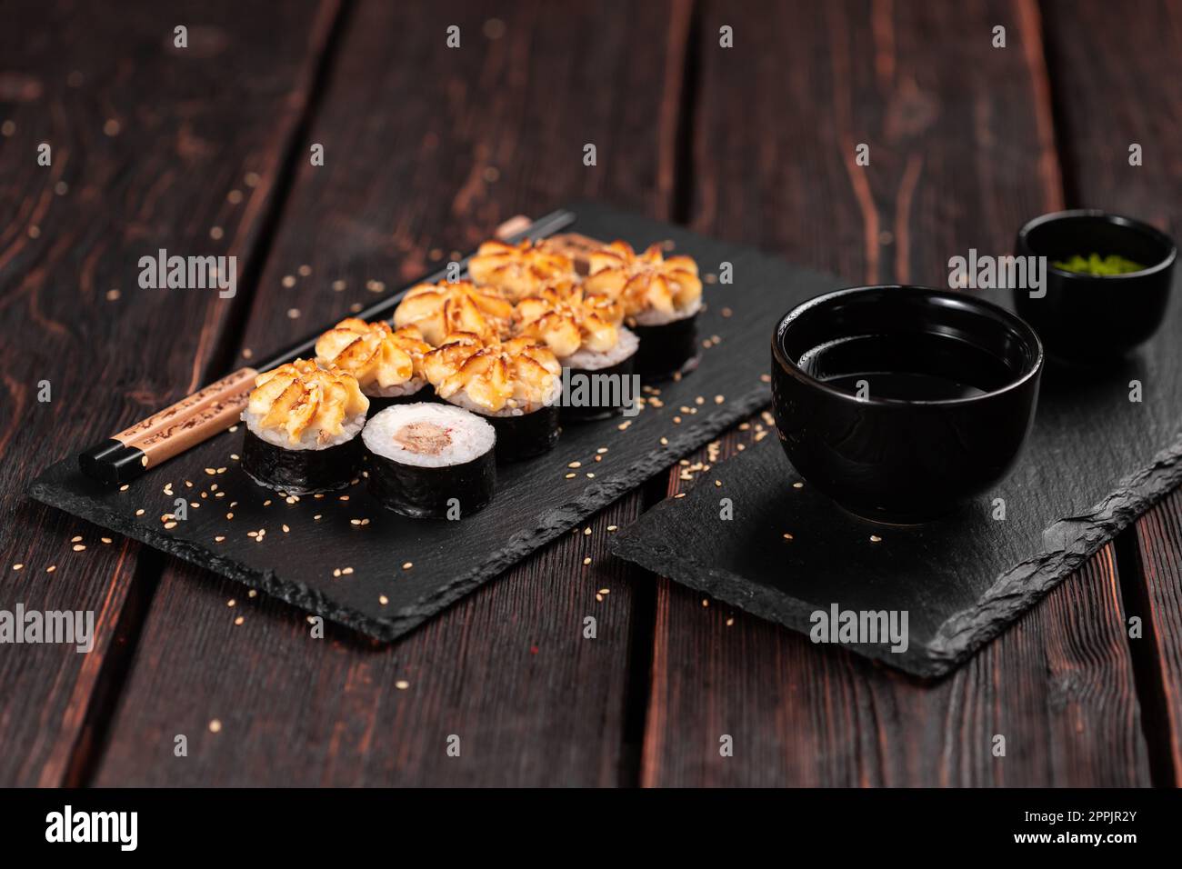 Maki Sushi Brötchen mit Aal serviert auf schwarzem Brett aus nächster Nähe - japanische Küche Stockfoto