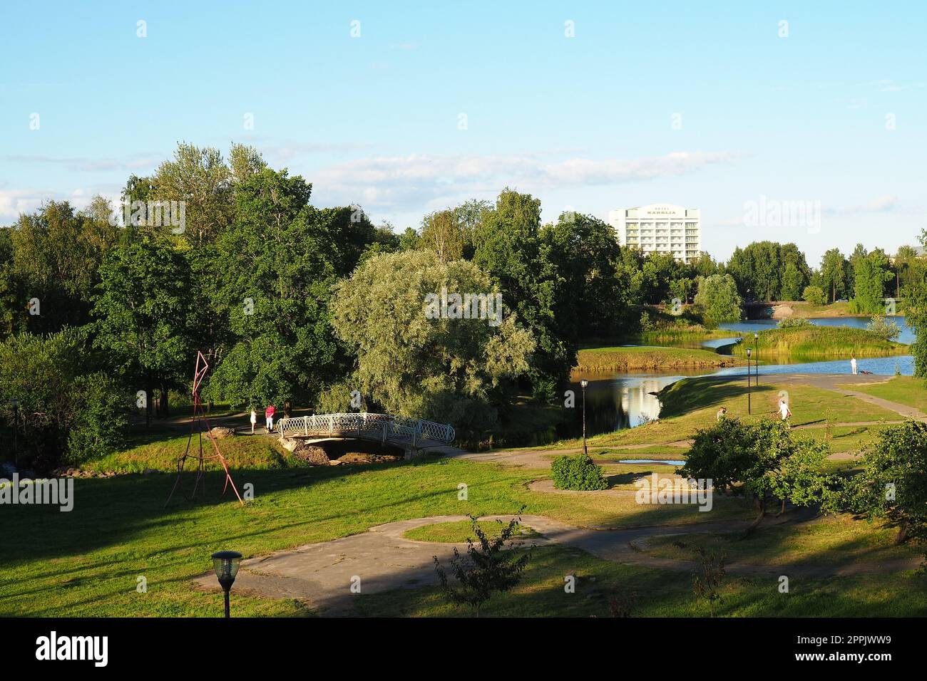 Mündung, Überschwemmungsgebiet und Terrassen des Flusses Lososinka, Petrozavodsk, Republik Karelien 3. August 2022. Sonniger, windloser Abend. Büsche und Bäume. Passanten überqueren den Fluss durch die Brücke. Stockfoto