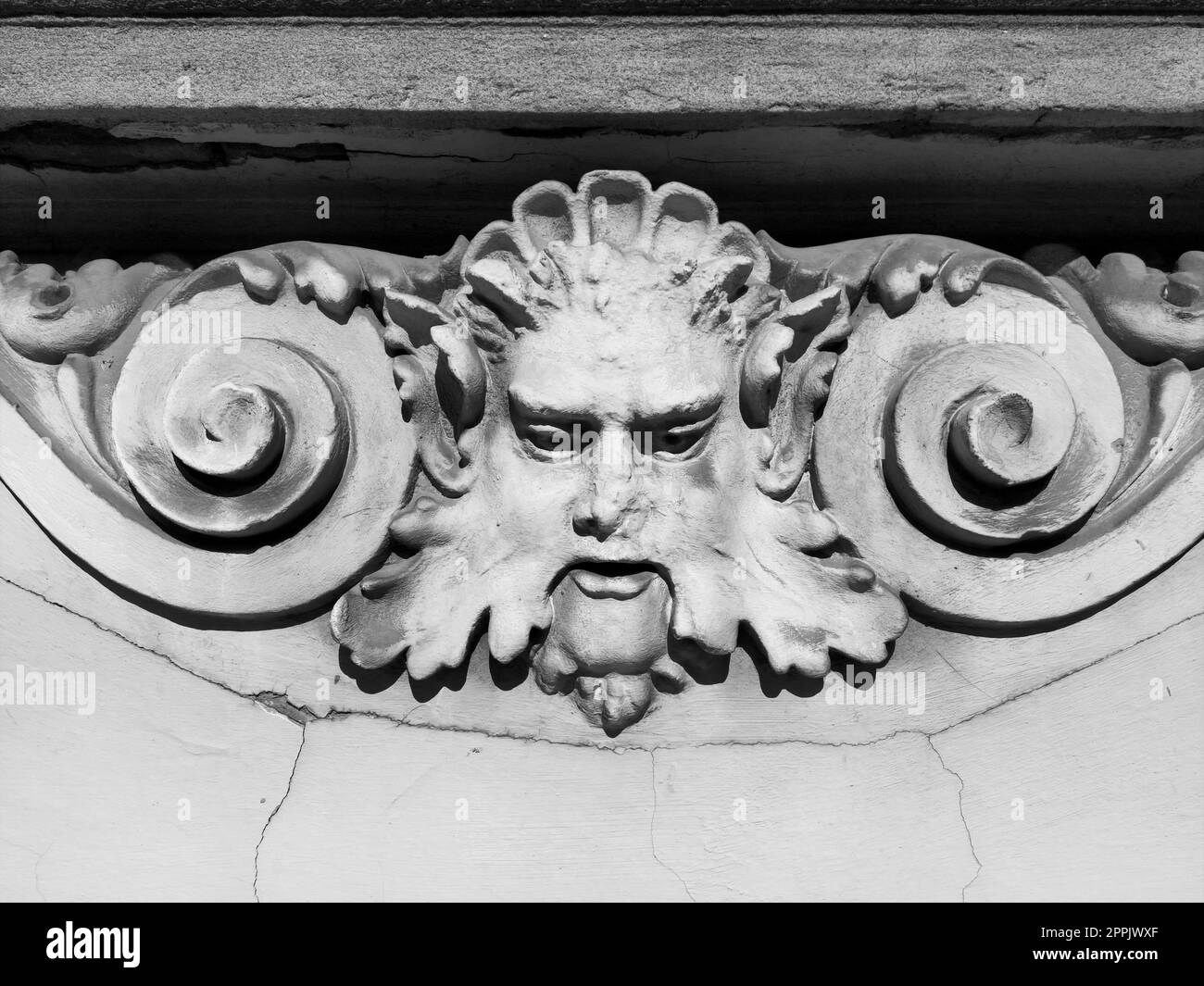 Dekorative Details an der Fassade. Relief an der Fassade eines Gebäudes. Stuckverzierung in Form eines Männerkopfes mit Locken, Schnurrbart und Locken an den Seiten. Hochentlasteter Beton. Stockfoto