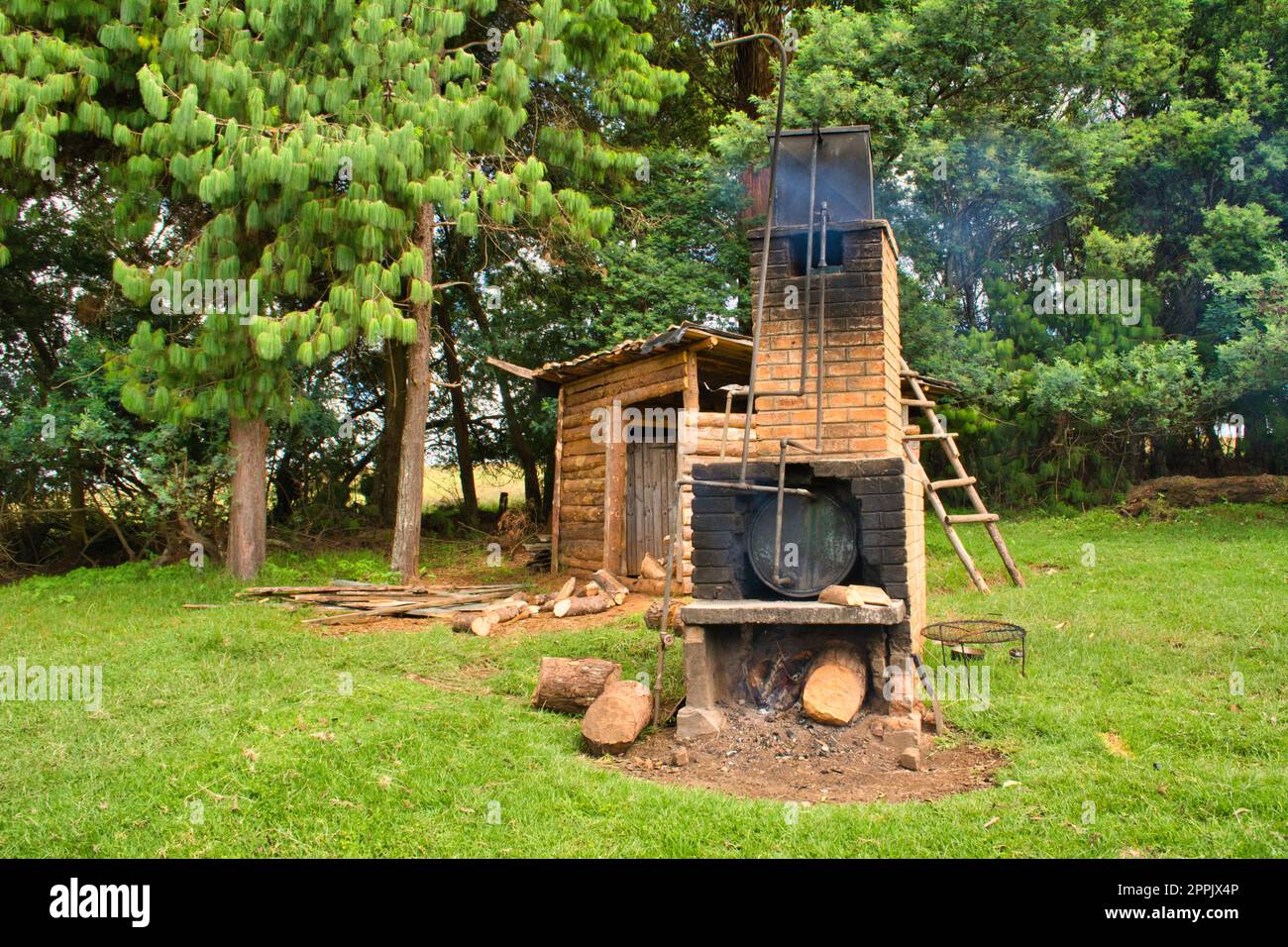 Holzofen im Freien, in dem Wasser für eine netzunabhängige Campingdusche erhitzt wird Stockfoto