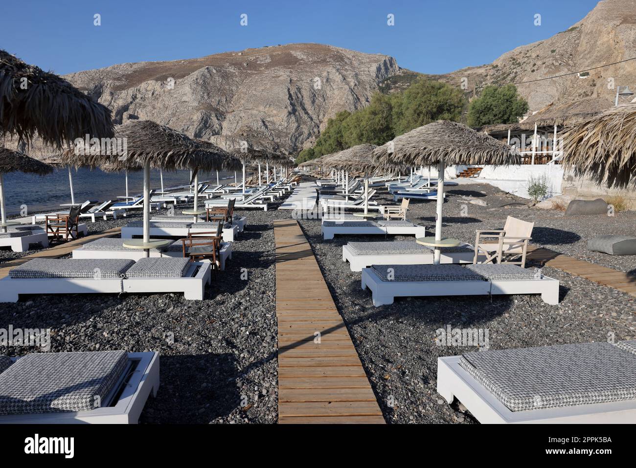 Sonnenliegen am schwarzen Vulkanstrand von Kamari in Santorini. Kykladen, Griechenland Stockfoto