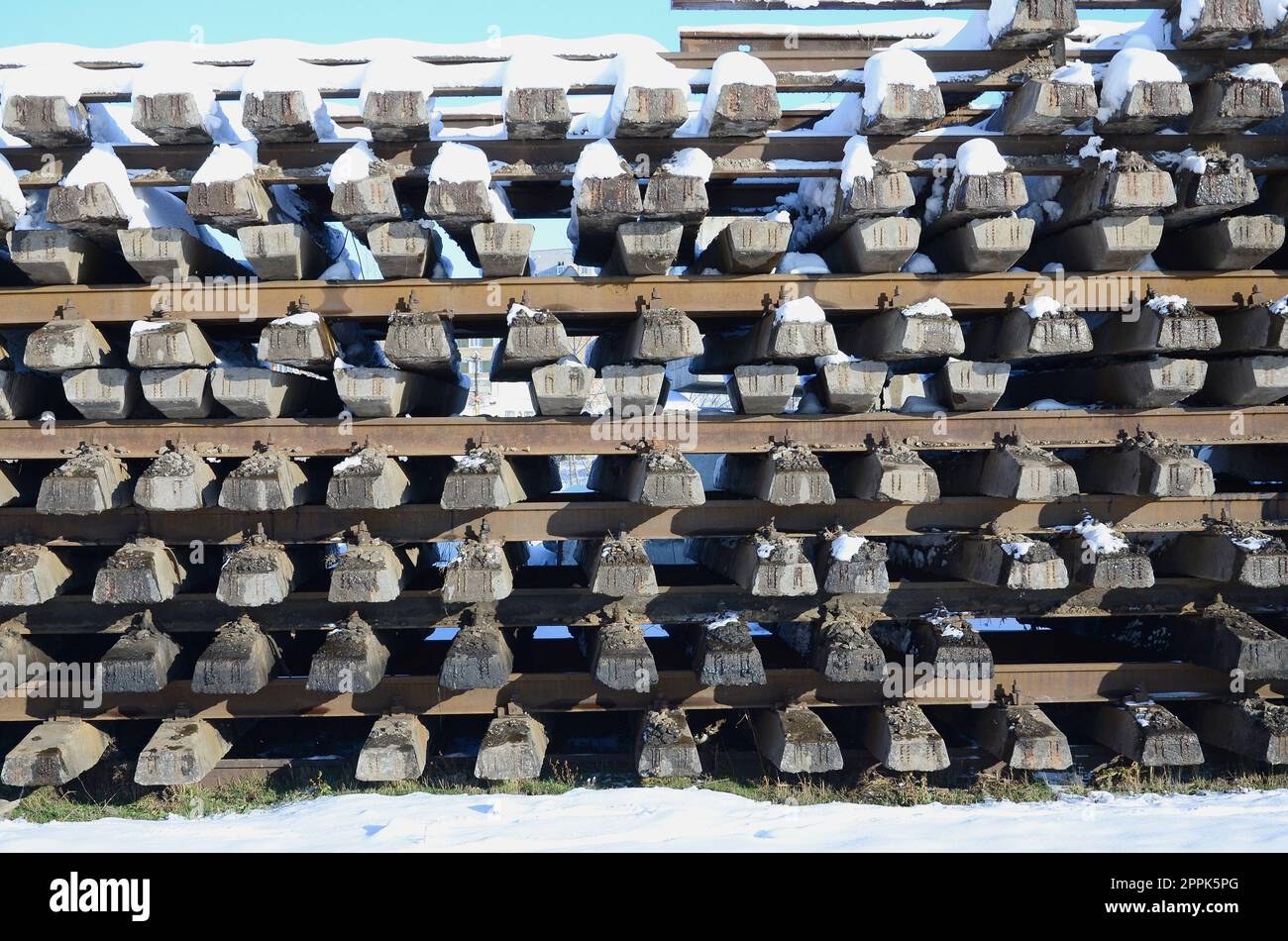 Im Winter werden viele alte Schienen und Schwellen in einem Eisenbahnlager gestapelt. Das Konzept der Erneuerung eines abgenutzten Eisenbahngleises Stockfoto