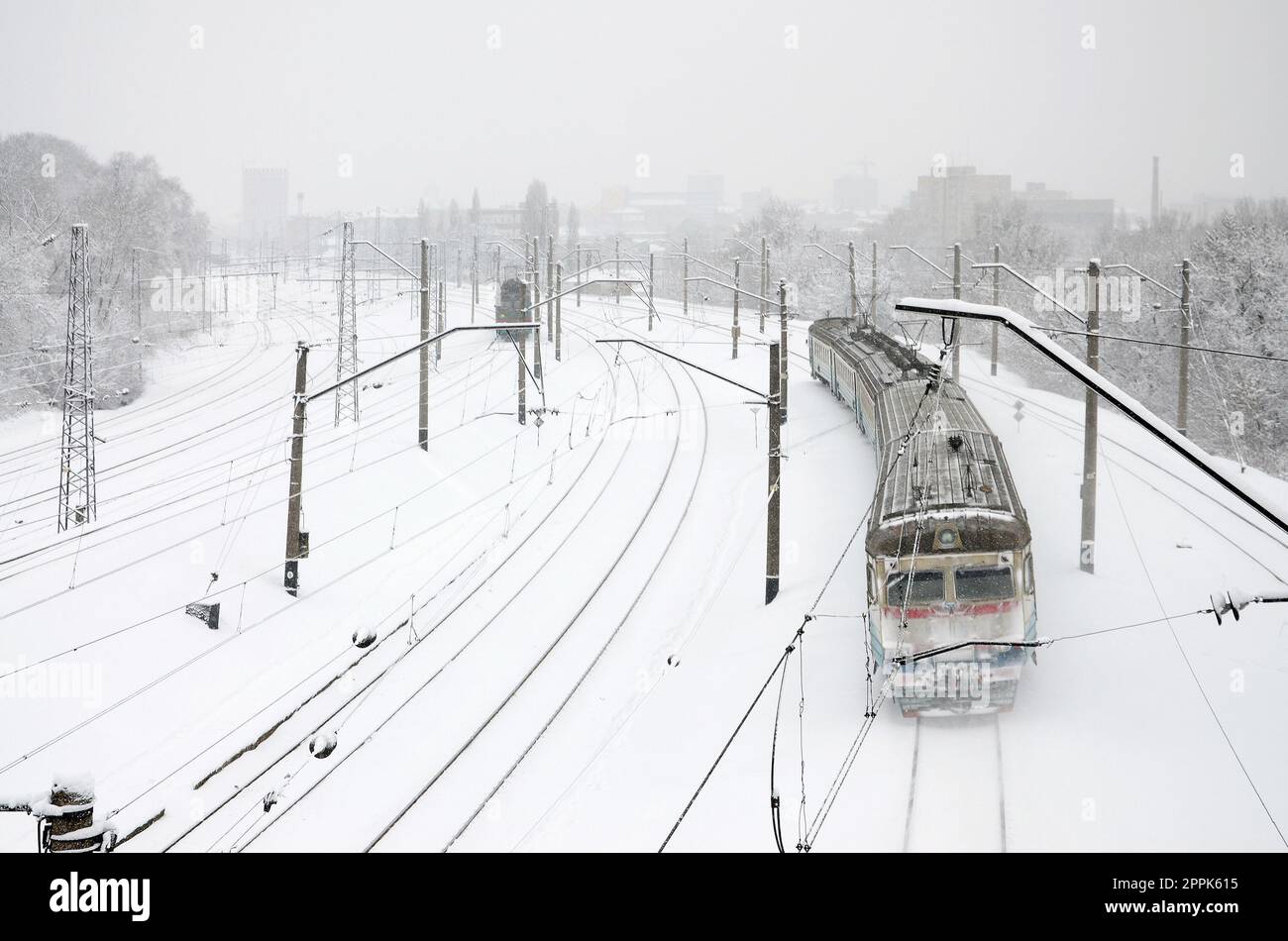 Ein langer Zug von Personenkraftwagen bewegt sich entlang der Eisenbahnstrecke. Eisenbahnlandschaft im Winter nach Schneefall Stockfoto