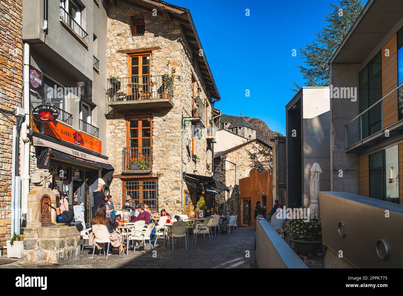 Alte enge, stimmungsvolle gepflasterte Straße mit Steingebäuden. Leute in Restaurants und Cafeterias, Andorra Stockfoto