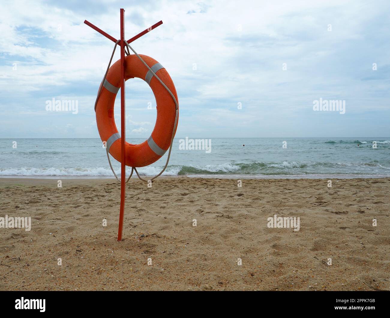 Rettungsschwimmer an einem Sandstrand. Orangefarbener Kreis an einer Stange, um im Meer ertrinkende Menschen zu retten. Rettungspunkt am Ufer. Himmel und Meer im Hintergrund. Stockfoto