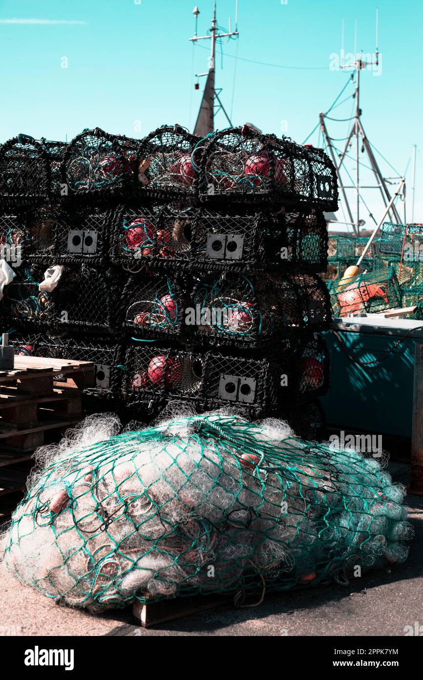 Auf dem Pier in einem Hafen gestapelte Fischernetze, Fischernetze und Boot aus nächster Nähe Stockfoto