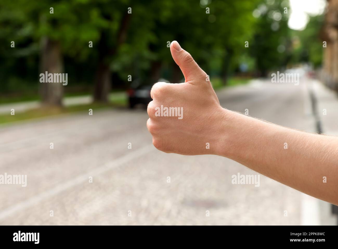 Mann, der ein Auto auf der Straße erwischt, Nahaufnahme und Platz für Text. Anhalter-Tour Stockfoto