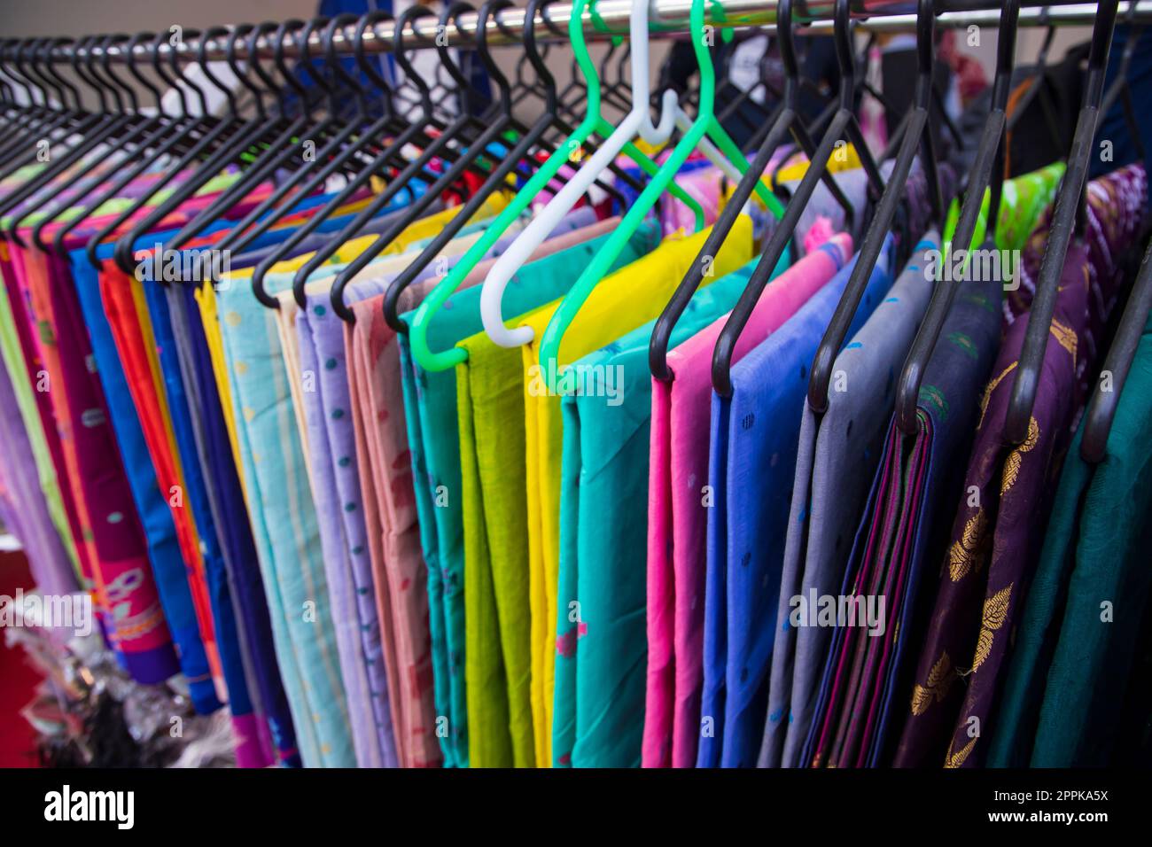Farbenfrohe Saree-Kleidung an Kleiderbügeln in einem Geschäft. Selektiver Fokus Stockfoto