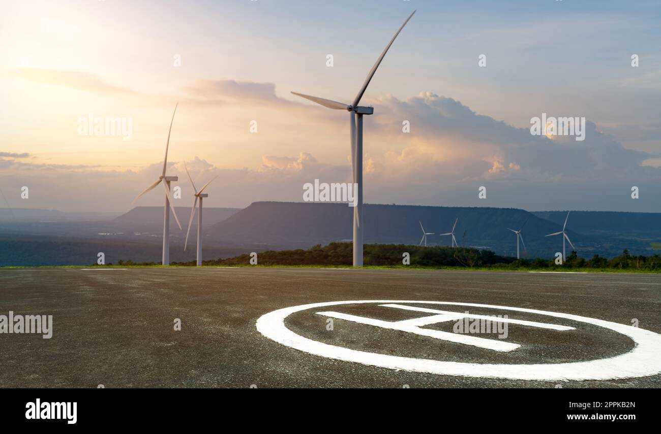 Asphalt-Hubschrauberlandeplatz und Windpark. Windenergie. Windkraft. Nachhaltige, erneuerbare Energien. Windturbinen erzeugen Strom. Plattform für Hubschrauber und Luftfahrzeuge mit vertikaler Start- und Landefähigkeit. Heliport eines Hubschraubers. Stockfoto