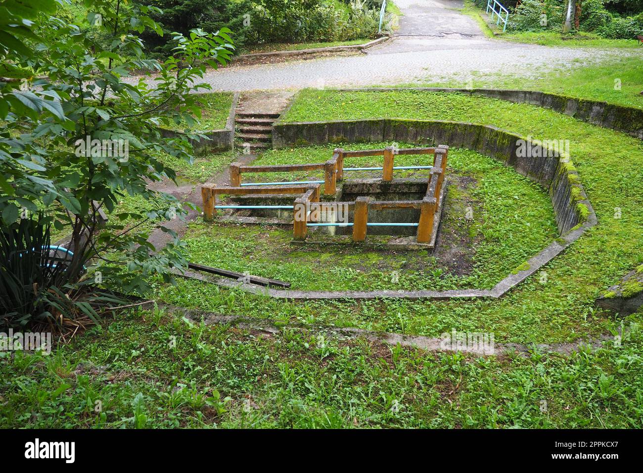 Banja Koviljaca, Loznica, Serbien. Berg Guchevo, Park und Wald. Quelle des Mineralschwefels und des eisenhaltigen Wassers Rakina Chesma Cesma. Eine Quelle in der Nähe der Straße nach Guchevo. Betonzaun und Treppen. Stockfoto