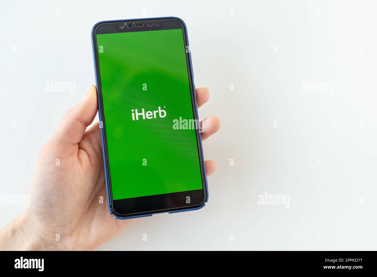 Kiew, Ukraine - 13. Dezember 2022: Frau, die ein Smartphone in der Hand hält, iPhone mit iHerb App im Internet-Store mit Logo auf dem Bildschirm Stockfoto