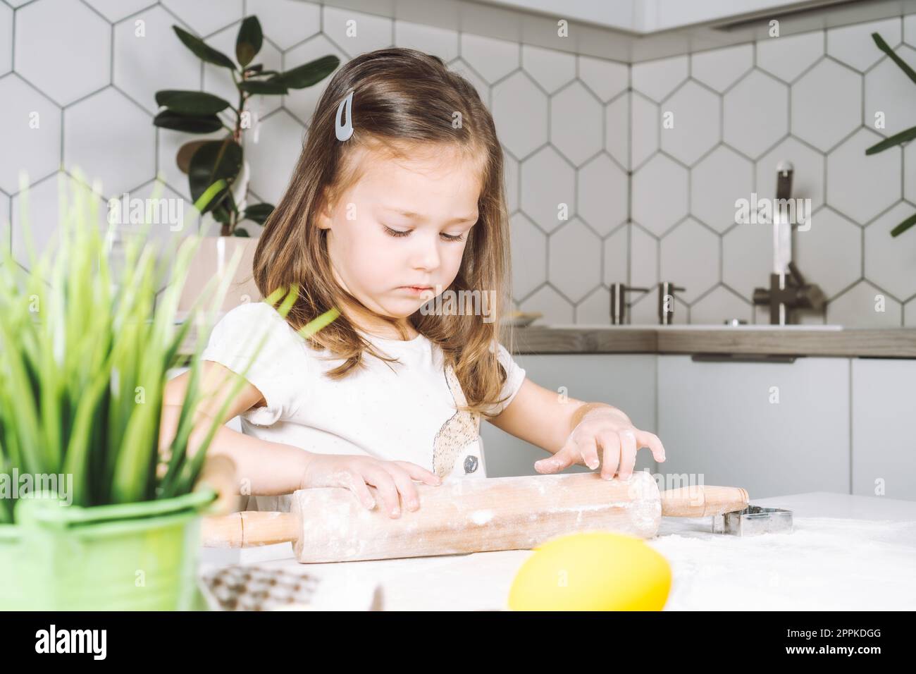 Porträt ein kleines, ernstes Mädchen, helft, lernt Teigrollen, macht osterkekse. Halten des Rollstifts. Nahaufnahme Stockfoto