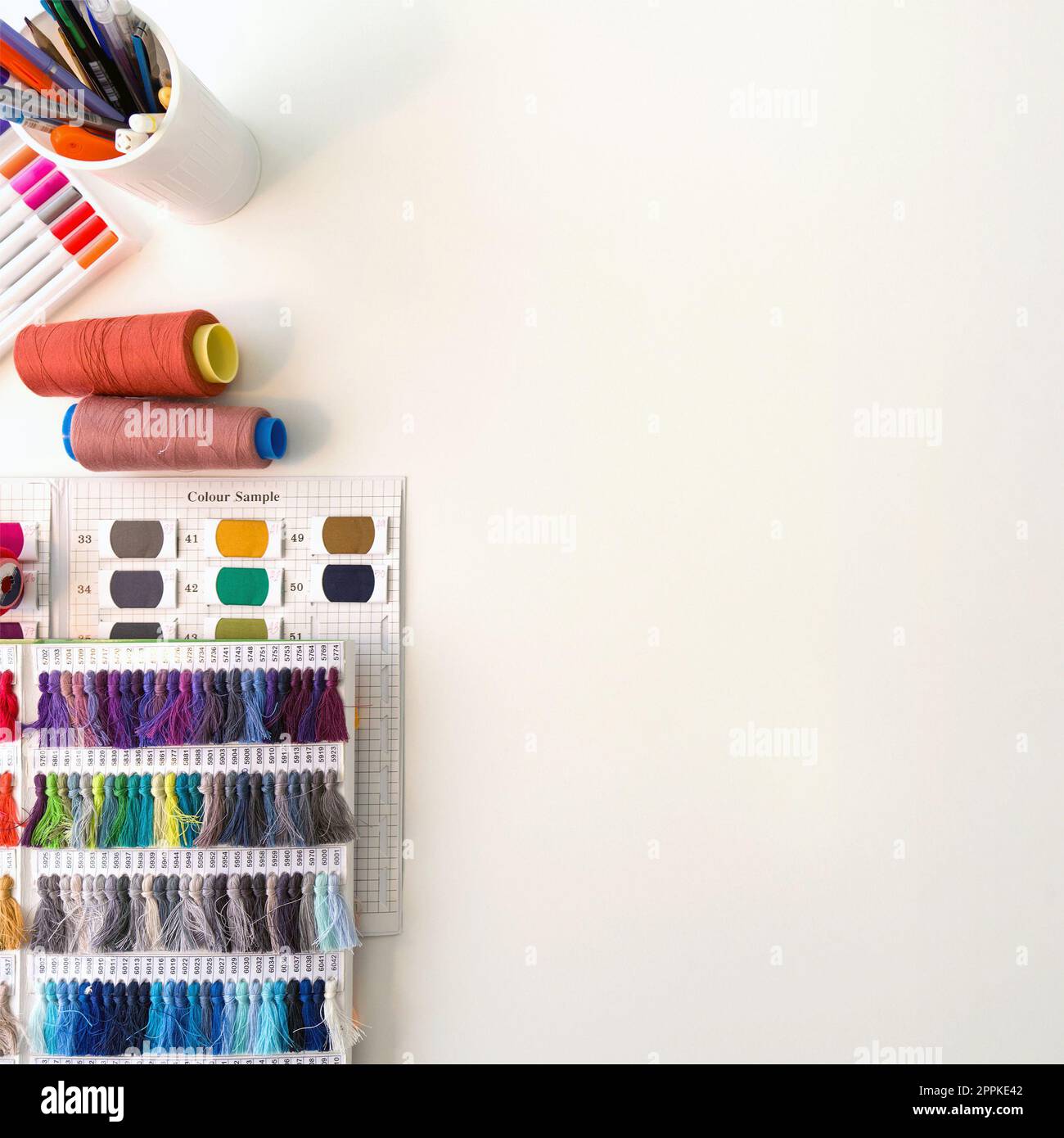Mehrfarbige magische Stifte, Farbmusterkatalog mit Seidenfaden, mehrfarbige Gewindespindel und Skizzieren auf einem großen Tisch. Draufsicht Stockfoto