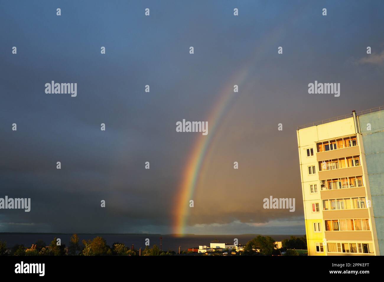 Petrozavodsk, Bezirk Klyuchevaya, Karelien, Russland, Juli 30, 2022. Doppelter mehrfarbiger Regenbogen über einem Apartmenthaus. Regen und dunkle Wolken über dem Onega-See. Goldene Stunde, blinder Regen, Sonnenstrahlen Stockfoto