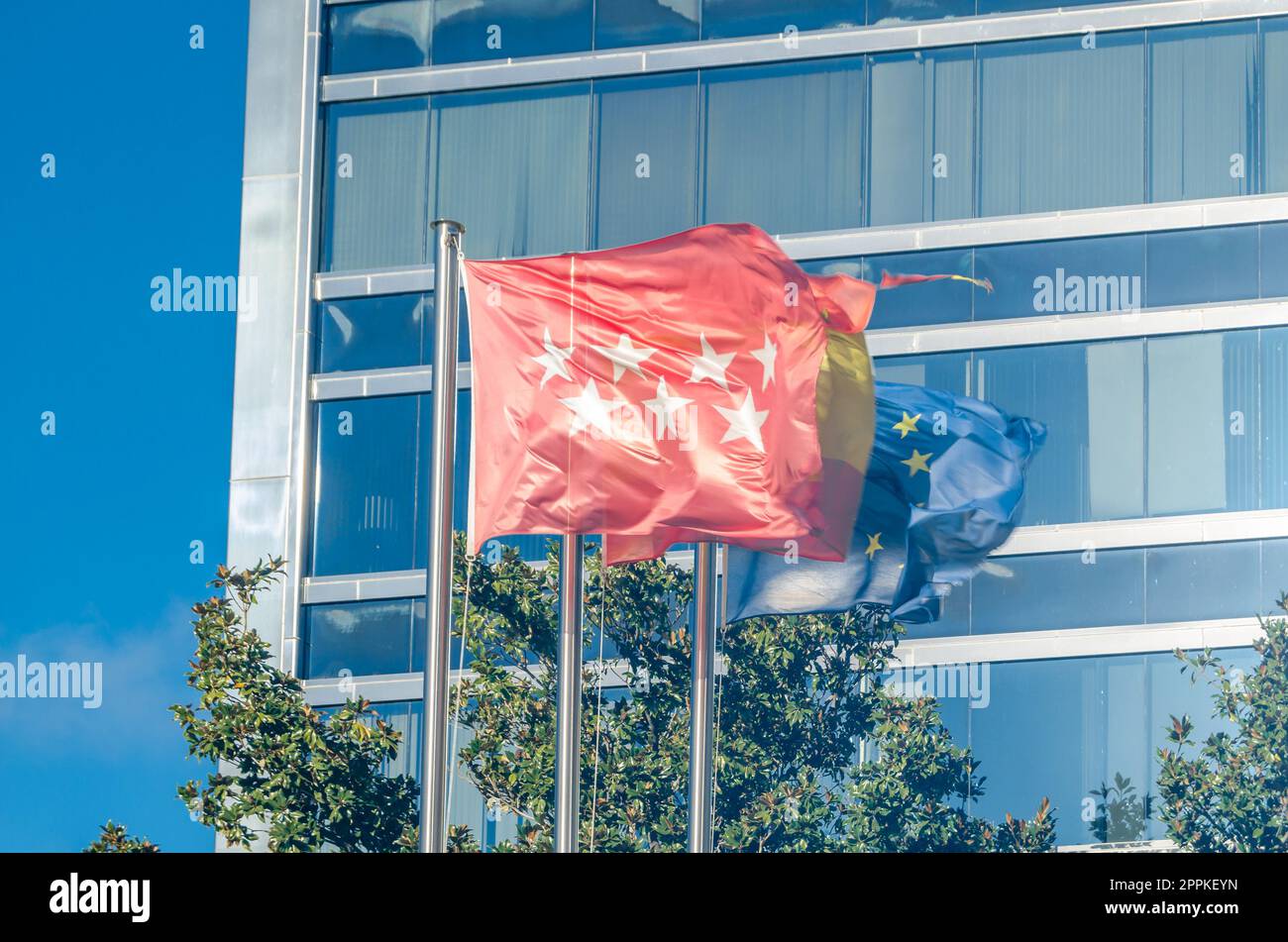 MADRID, SPANIEN - 27. DEZEMBER 2021: Flaggen der Gemeinschaft Madrid, Spaniens und der Europäischen Union vor dem Sitz von Acerinox in Madrid, Spanien. Acerinox ist ein in Spanien ansässiger Konzern zur Herstellung von Edelstahl Stockfoto