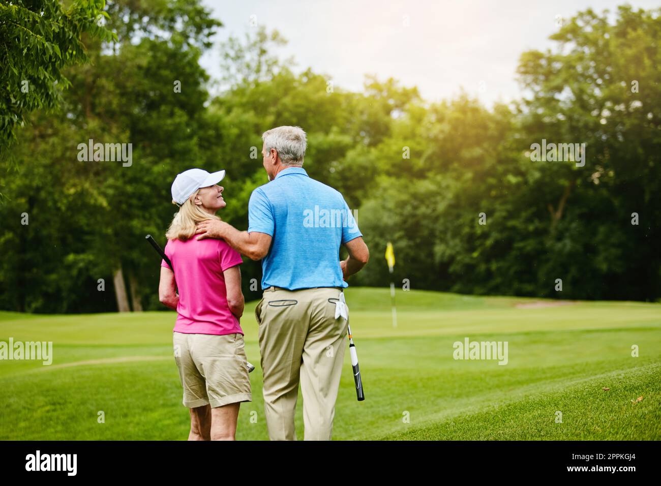 Machen wir einen romantischen Spaziergang in Richtung unseres Kurses. Ein reifes Paar auf einem Golfplatz. Stockfoto