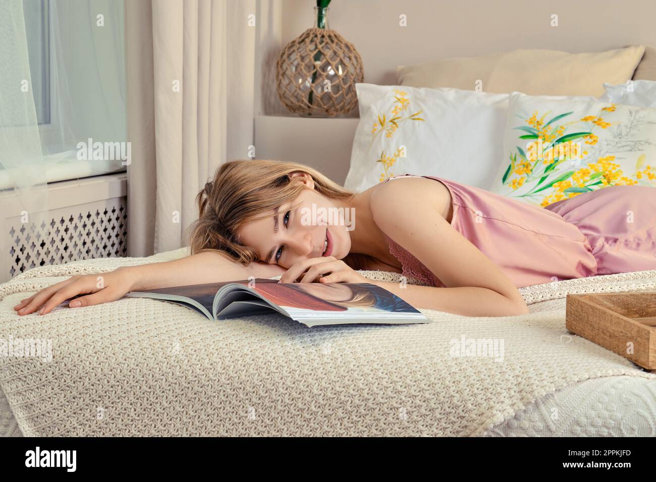 Nettes Mädchen in Seide Schlafanzug im Bett durch einen Magazin Stockfoto