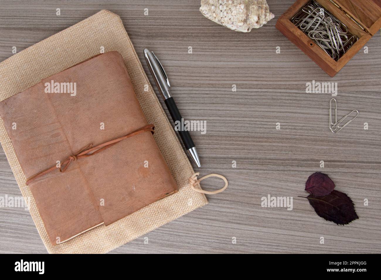 Flacher Blick auf ein Buch mit Lederbindung mit Stift und Büroklammern Stockfoto
