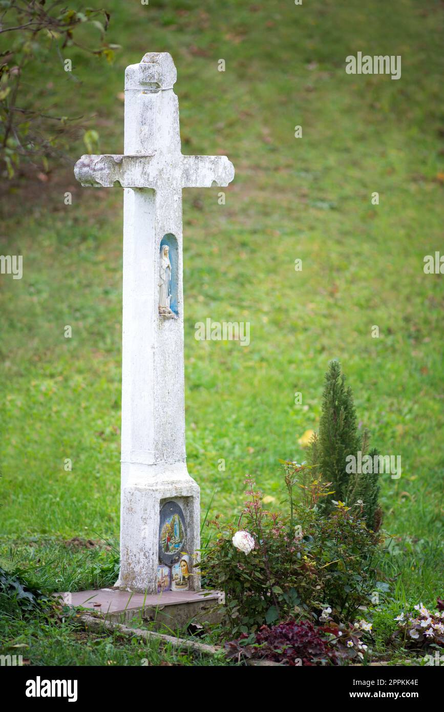 Naiv-Skulptur der madonna auf einem weißen Kreuz eines alten Grabes Stockfoto