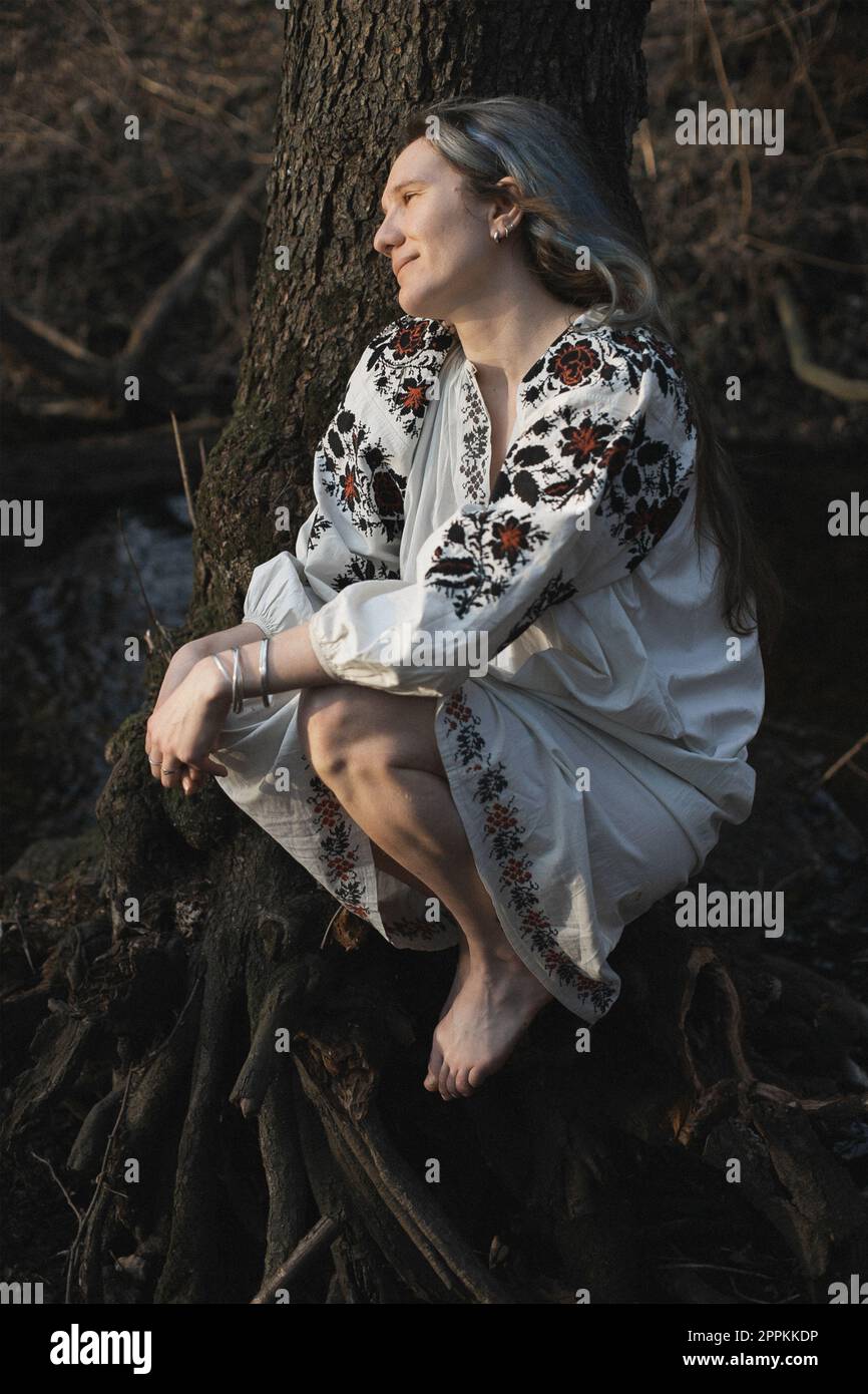 Eine lächelnde Frau aus nächster Nähe in einer ukrainischen Chemie und ein stummes Waldporträt Stockfoto