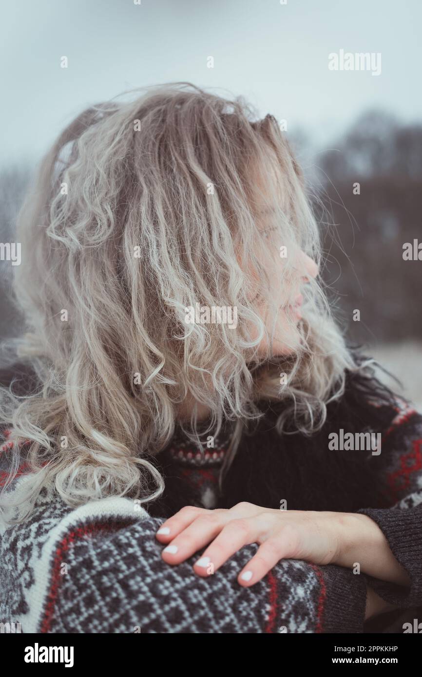 Nahaufnahme einer Frau mit lockigem Haar in einem warmen Pullover im Außenporträt Stockfoto
